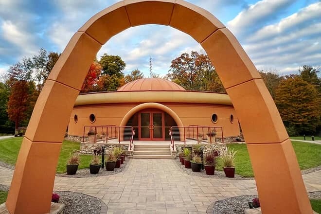 An arched gateway framing the domed temple, surrounded by autumn trees