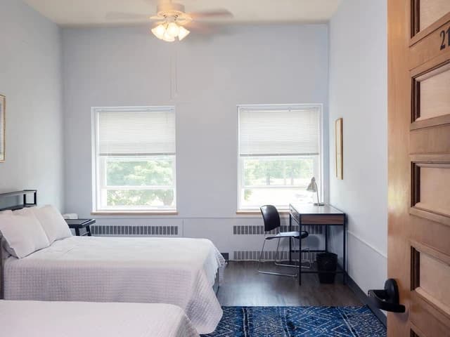 The Standard Select Plus room with two beds, a ceiling fan, and two windows