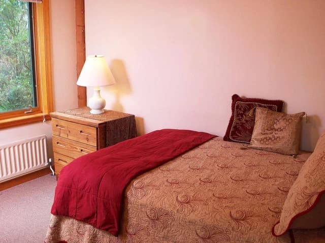 A guest house suite bedroom with a bed and a dresser beside a window